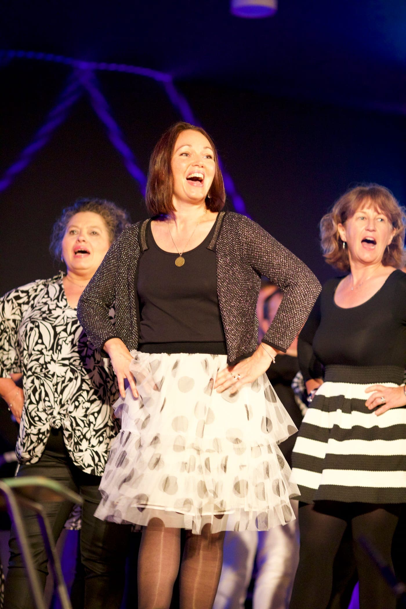 Choristes féminines chantant en trio sur scène illuminée
