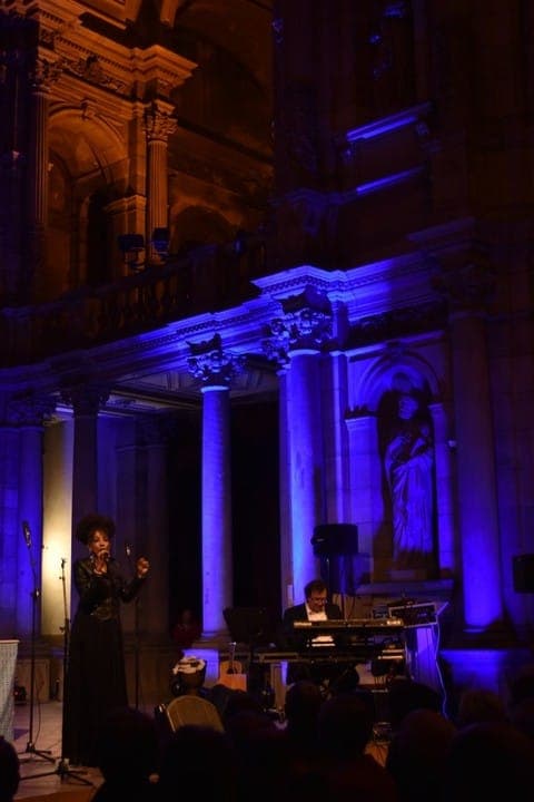 Chanteuse soliste au micro et claviériste, concert gospel dans une église en lumière bleue