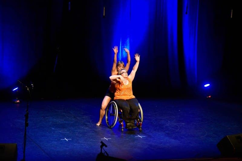 Danseur en fauteuil roulant triomphant sous projecteurs bleus