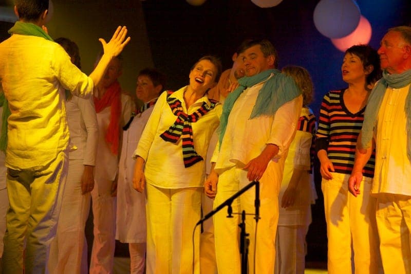 Choristes de La Cécilia en costumes jaune et blanc sur scène
